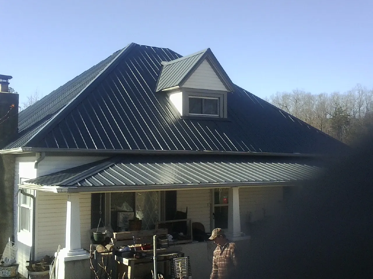 Dark blue standing seam metal roof with a dormer above a front porch in Rossville