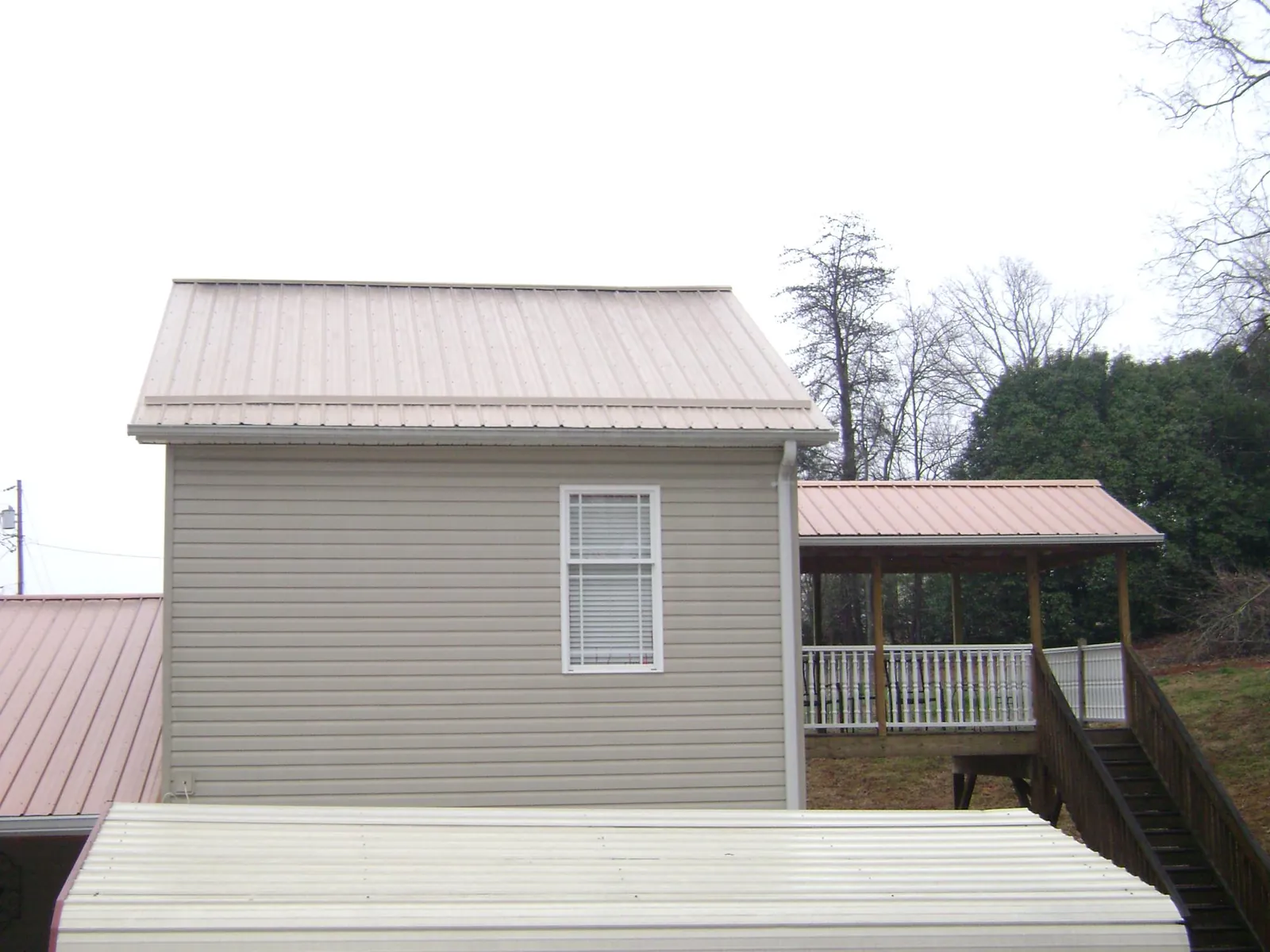 Tan metal roofs on a two story addition and attached porch, from a Roof Replacement job in Rossville
